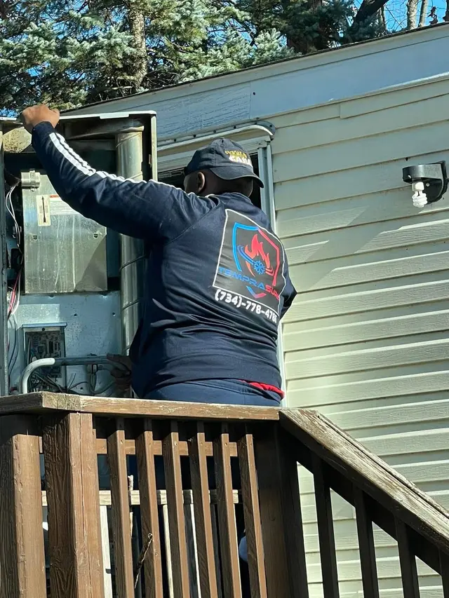 Al from Temprasure in a company jacket servicing a package heating and cooling unit on a manufactured home